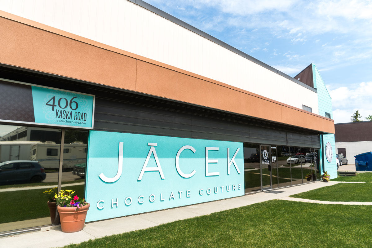Image of The exterior of the JACEK Studio. A large teal wall is featured, which reads